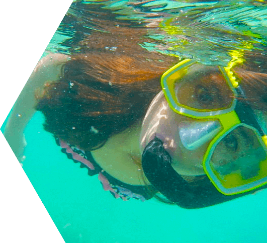 Close-up of a young girl underwater wearing a mask and breathing through a snorkel