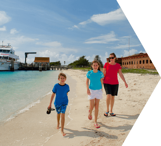 A mom and her young daughter and son walking along the shoreline in the Dry Tortugas National Park