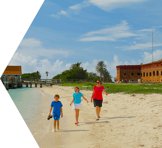 A mother and children walking along the shore of the Seaplane Beach at the Dry Tortugas National Park