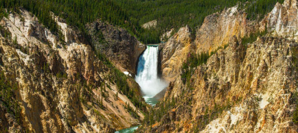 Una cascata circondata da ripide montagne rocciose e lussureggiante deserto nel Parco Nazionale di Yellowstone